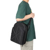 A person wearing a dark green t-shirt is holding a black storage bag.
