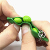 A hand holds a green silicone fidget toy keychain with a small face on it.
