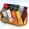 A collection of canvas cotton bag straps in various colors and shades, featuring metal hooks, displayed in a woven basket.