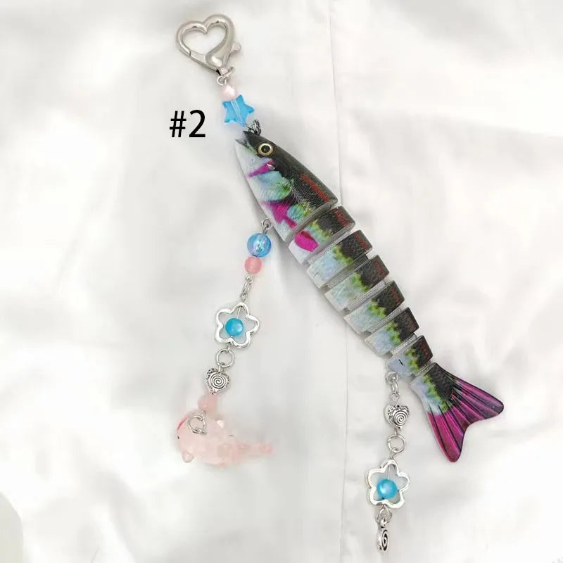 A silver acrylic keychain charm shaped like a fish with colorful accents and a heart loop.