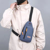 A person wearing a beige jacket is holding a navy blue lightweight oxford cloth crossbody bag.