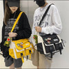 A woman is holding a yellow and black nylon crossbody shoulder bag with a white sweatshirt.