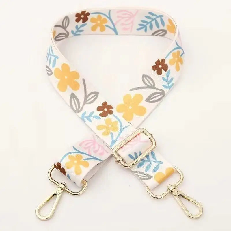 A beige nylon strap with a floral pattern featuring yellow and brown flowers, used for bags or luggage.