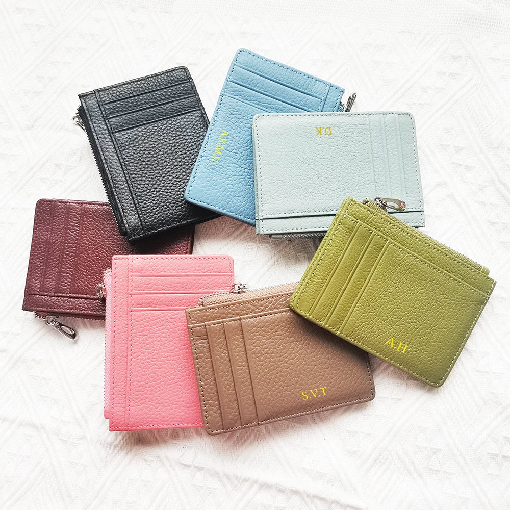 A collection of six genuine leather zipper card holders and coin purses in various shades of pink, mint green, and olive.
