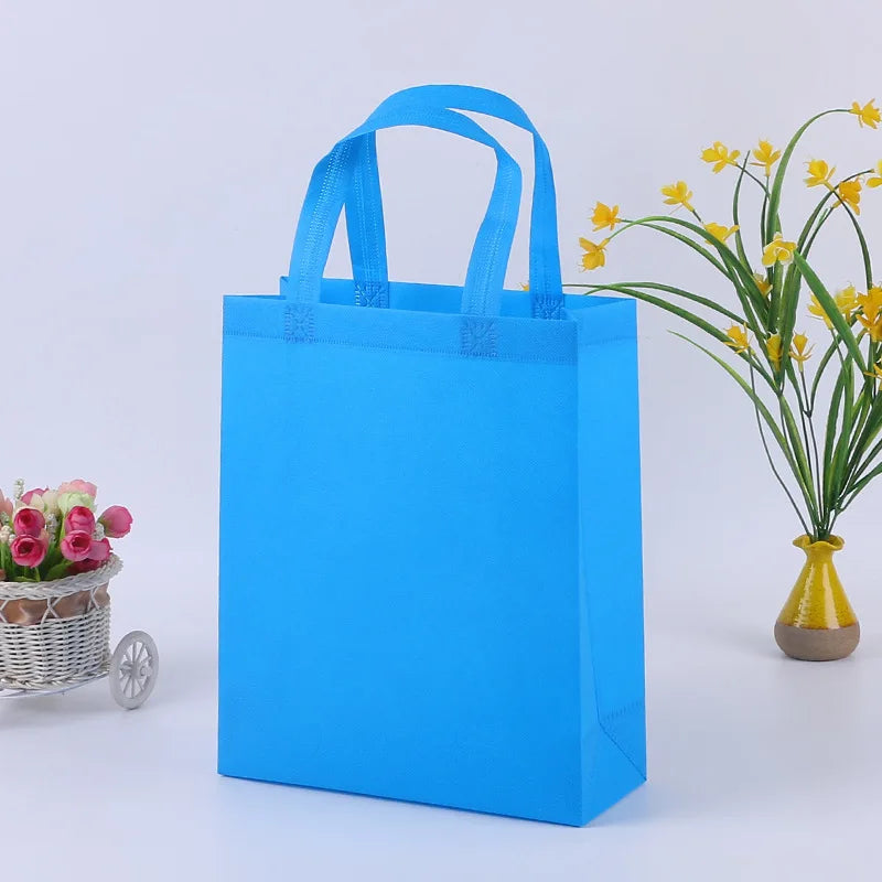Helles blaues nichtgewebtes Einkaufstaschenbeutel mit Henkeln neben einer Vase mit gelben Blumen.