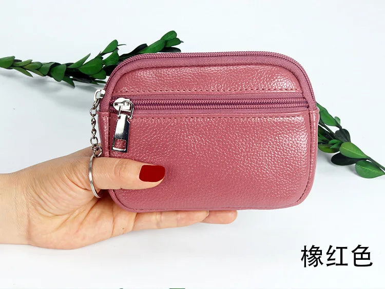 A hand holds a pink PU leather mini wallet with a silver keychain against a white background.