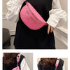 A pink PU leather multi-pocket crossbody bag is shown being held by a woman against a black top.