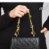 A black quilted leather handbag with a gold chain pendant is shown against a dark background.