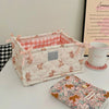 A quilted cotton storage basket with a lace flower design featuring pink and white patterns.