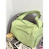 A lime green canvas crossbody travel tote bag with a zippered pocket resting on a gray surface.