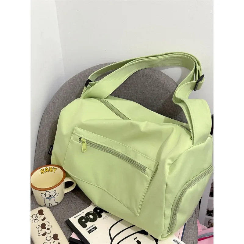 A lime green canvas crossbody travel tote bag with a zippered pocket resting on a gray surface.