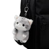 A grey soft cat plush pendant hanging from a chain attached to a black backpack.