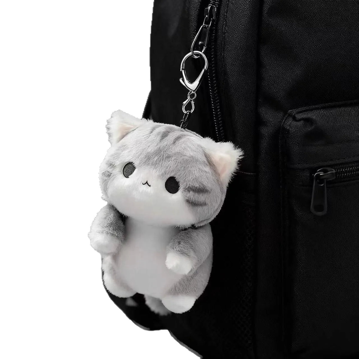 A grey soft cat plush pendant hanging from a chain attached to a black backpack.
