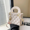 A light pink quilted leather crossbody handbag with gold chain accents resting on a white surface.