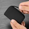 A hand holds a black RFID zipper wallet with a quilted texture against a gray wooden background.