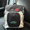 A gray and white backpack featuring a cow print design and a black front pocket with the text Welcome Friends!