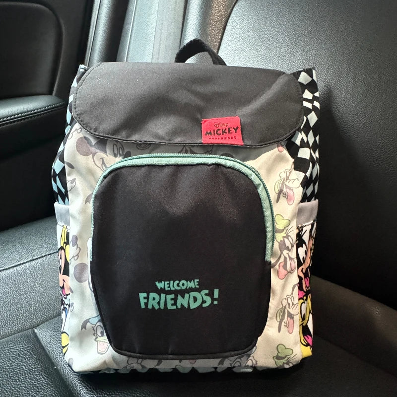A gray and white backpack featuring a cow print design and a black front pocket with the text Welcome Friends!