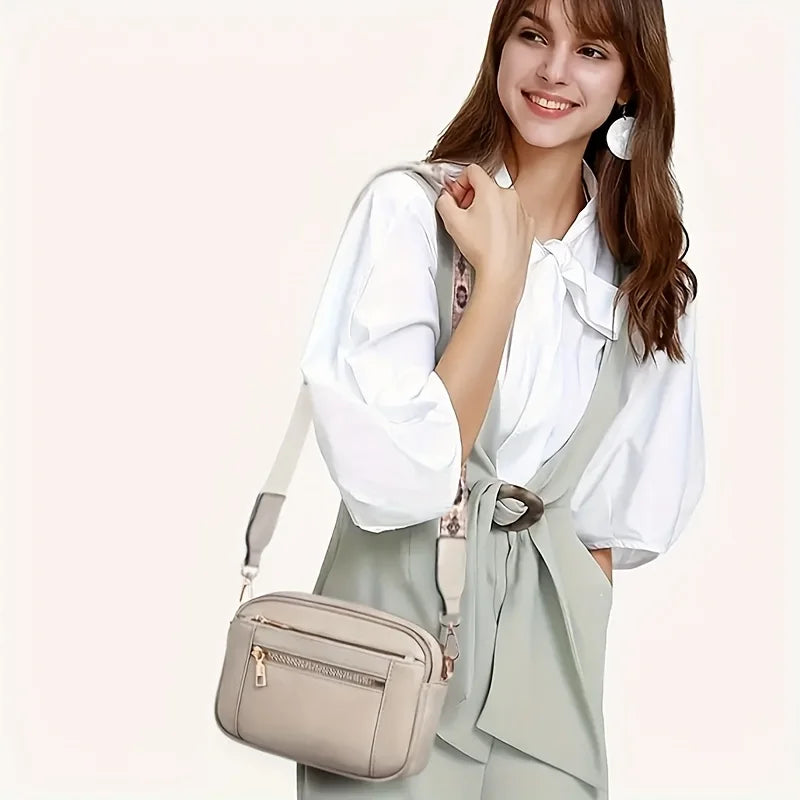 A woman models a beige PU leather crossbody bag with multiple pockets and a light green collared shirt.
