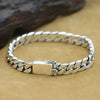 Sterling silver punk charm bracelet with a padlock clasp resting on a brown surface.