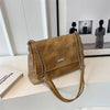 Bolso de cuero con cadena retro sobre una superficie blanca junto a una foto enmarcada.