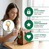 A woman is shown assembling a gold and enamel four-leaf clover keychain, highlighting easy attachment, quality craftsmanship,