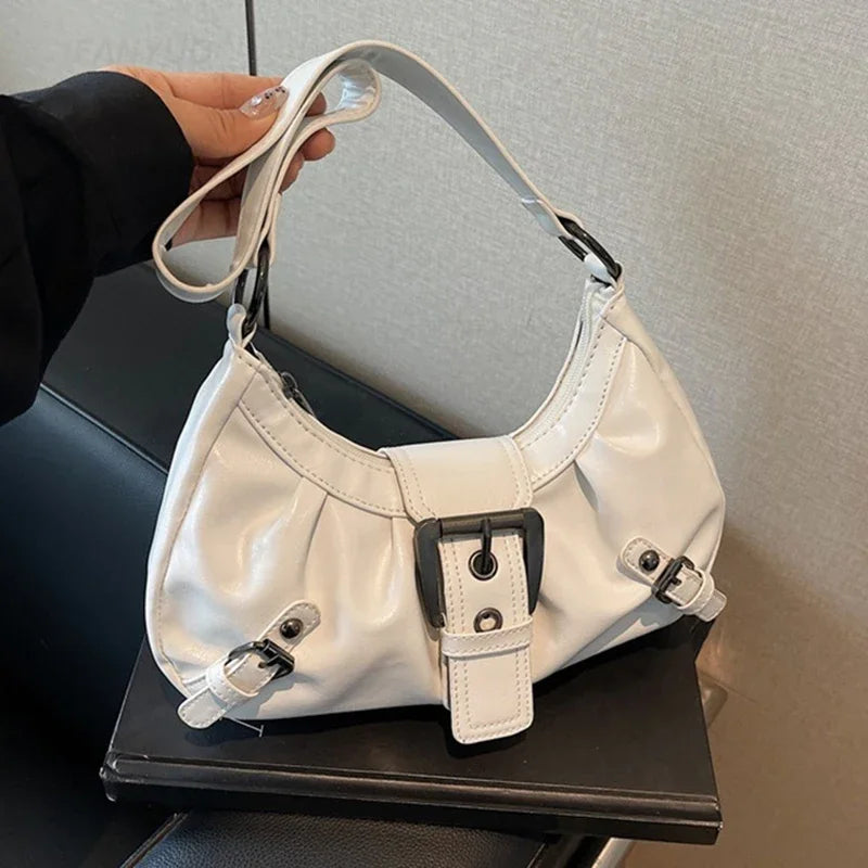Weiße Y2K-Retro-Plissee-Schultertasche wird von einer Hand gehalten, auf einer dunklen Oberfläche dargestellt.