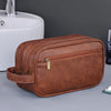A brown leather toiletry bag is shown next to a white ceramic sink.