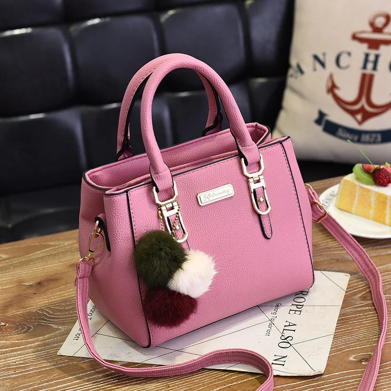A pink vintage PU leather tassel handbag resting on a wooden surface.