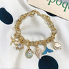 Gold chain bracelet featuring an ocean pearl charm, starfish, and shell accents.
