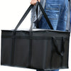 A black reusable insulated warming bag is being held by a person, shown from the side.