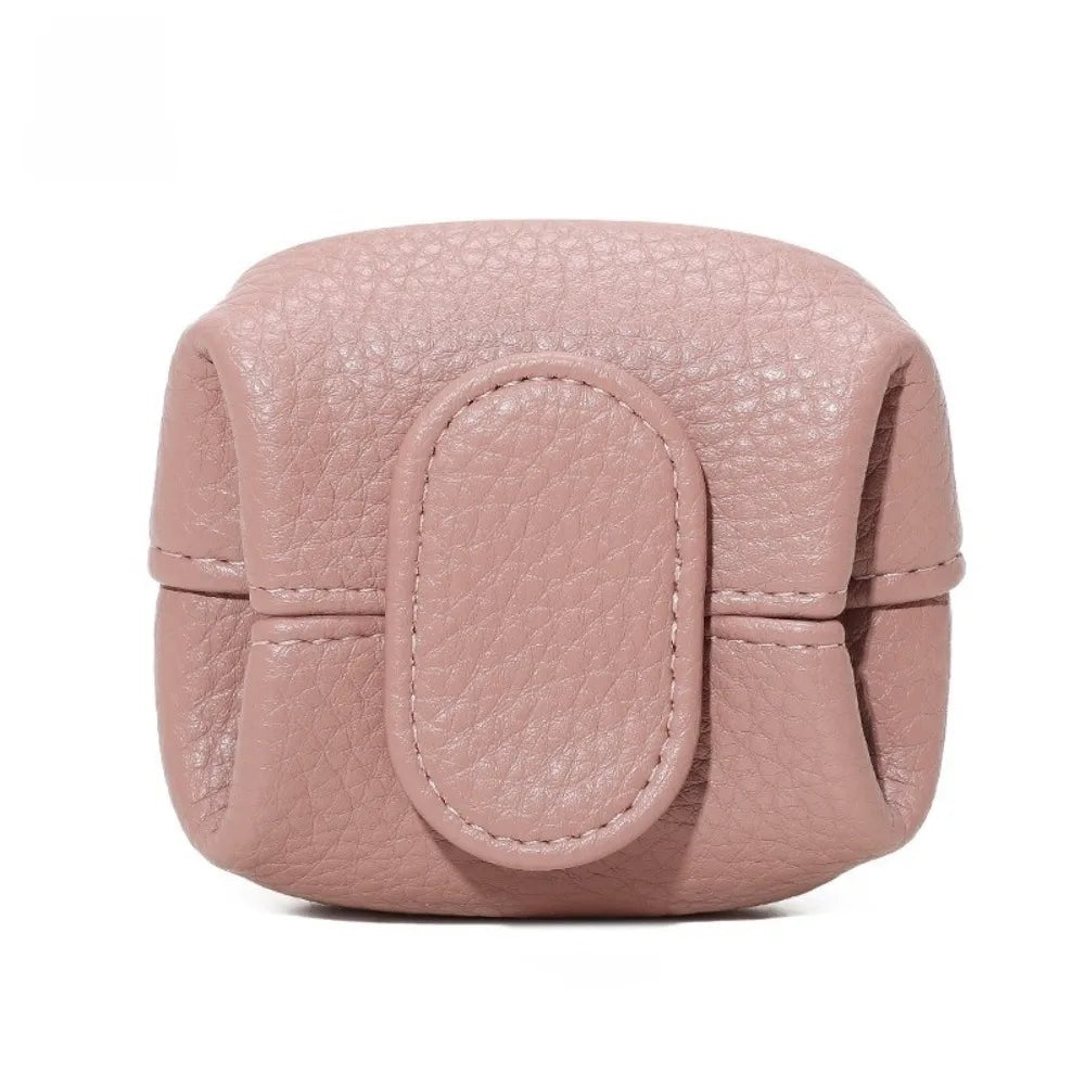 A round, pink faux leather coin purse with a snap closure and textured finish.