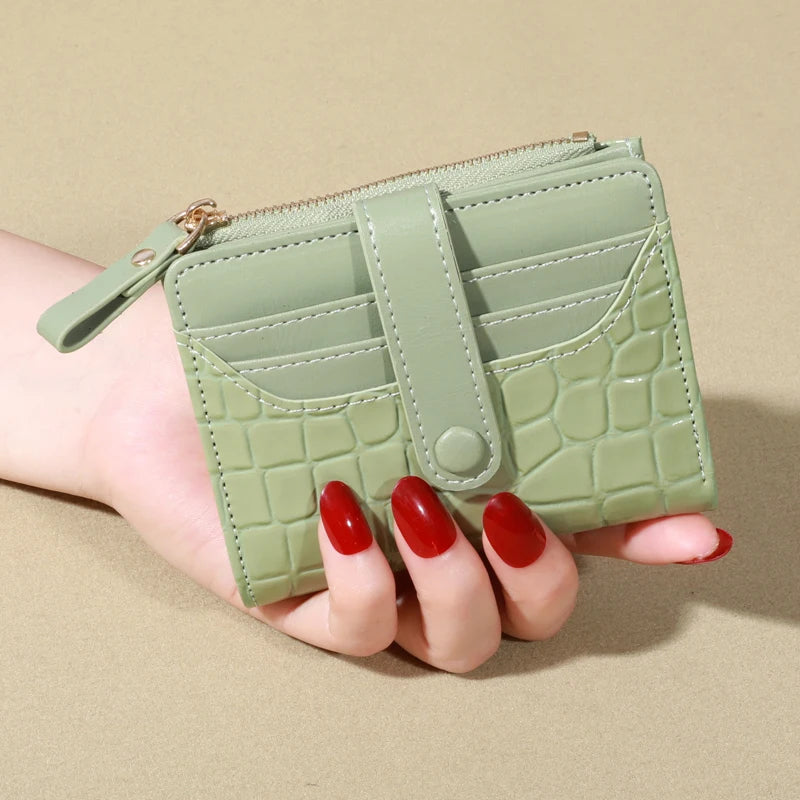 A hand holds a light green PU leather card wallet with a double zip closure.