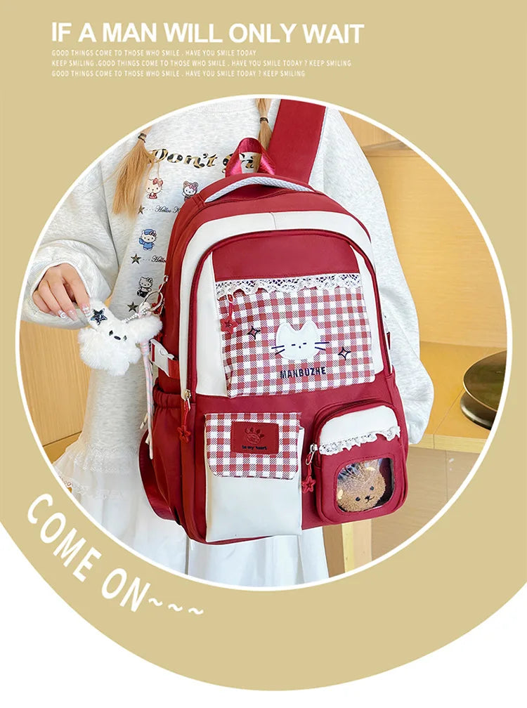 A maroon and white Oxford backpack featuring a patterned fabric, a cat design, and a small pouch.