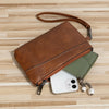 A brown retro PU leather zipper wrist bag rests on a light wooden surface next to a white smartphone.