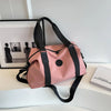 A pink versatile oxford cloth travel tote bag with black straps resting on a white surface.