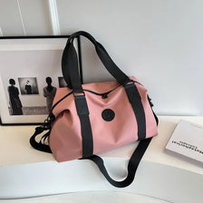 A pink versatile oxford cloth travel tote bag with black straps resting on a white surface.