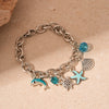 Silver chain bracelet featuring an ocean pearl charm with starfish and shell accents