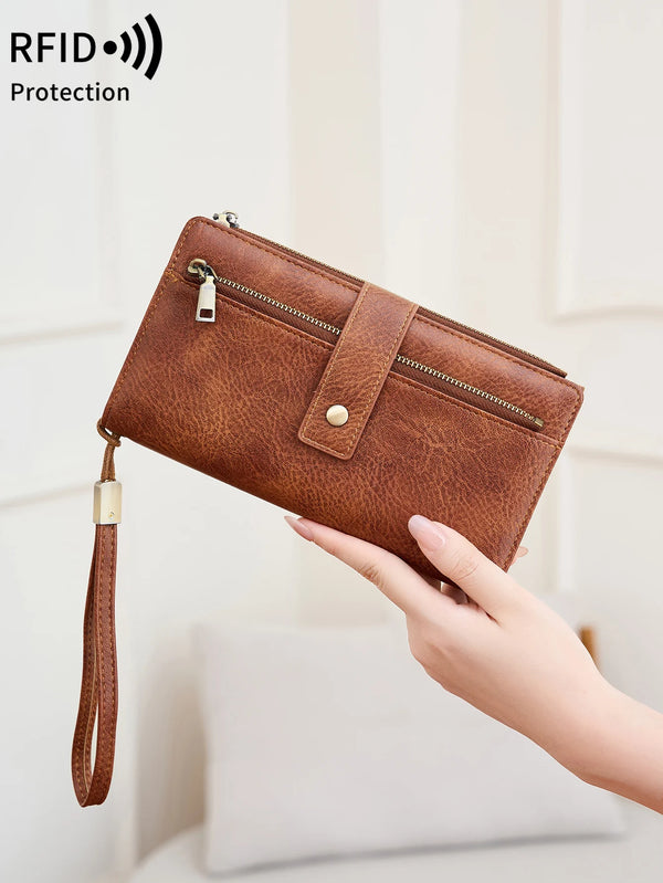 A brown vintage PU leather clutch wallet is being held by a hand, showing its texture and design.