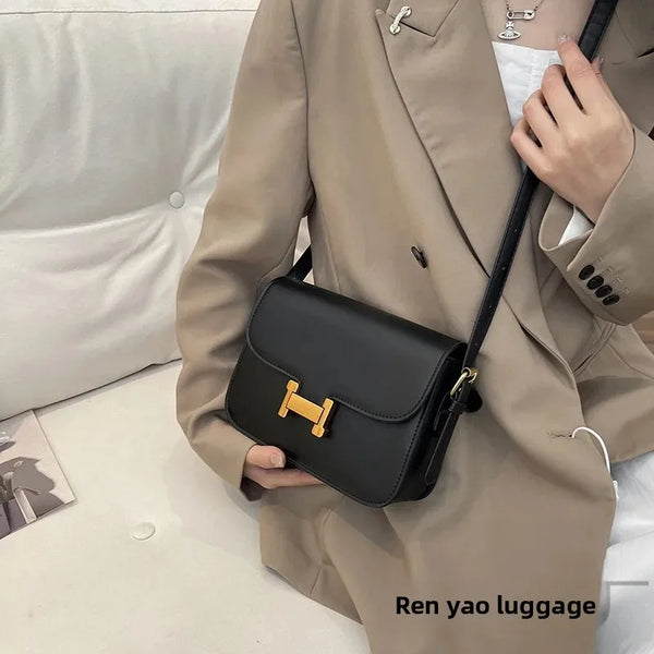 A beige trench coat is shown holding a black leather single shoulder bag with gold hardware.