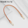 A tan leather strap with gold hardware is shown against a white background.