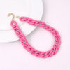A pink acrylic statement choker necklace with a gold-colored clasp is displayed on a white background.