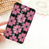 A pink and black patterned card holder featuring a repeating flower design, held by a hand on a white surface.