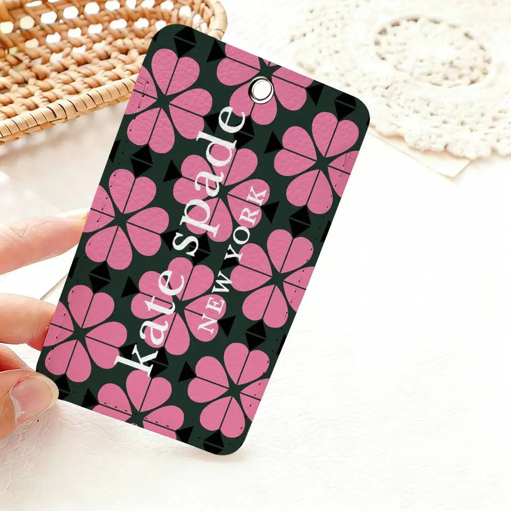 A pink and black patterned card holder featuring a repeating flower design, held by a hand on a white surface.