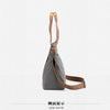 Side view of a gray canvas tote bag with tan leather straps.