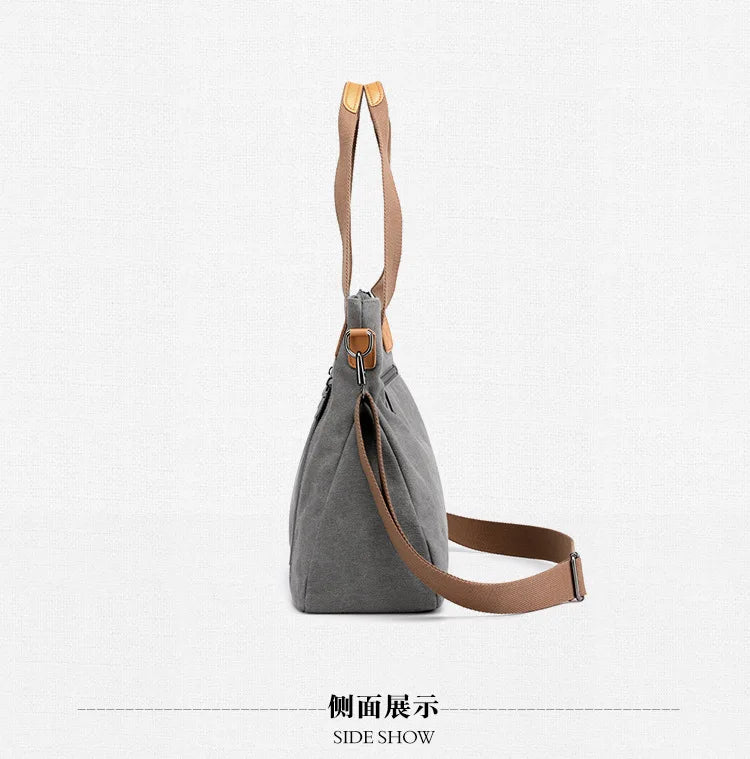 Side view of a gray canvas tote bag with tan leather straps.