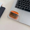 An orange translucent silicone case for AirPods resting on a silver laptop keyboard.