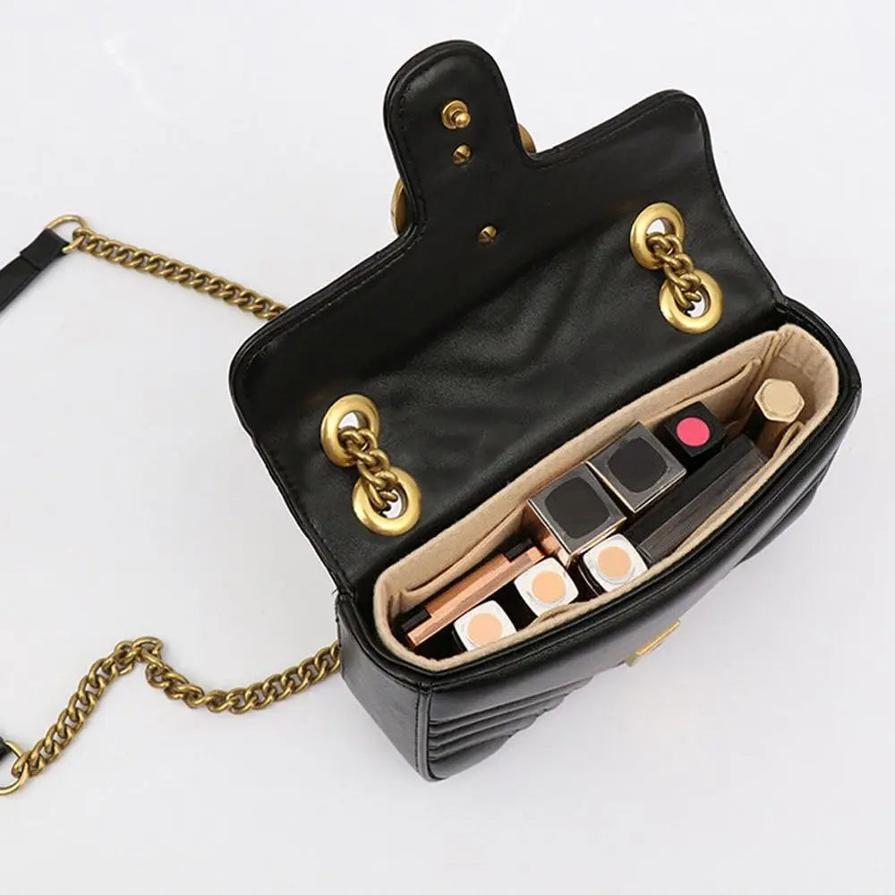 Schwarze Filthandtasche-Organizer-Einlage mit goldenen Kettenriemen und einem Reißverschlussfach für Make-up-Produkte.