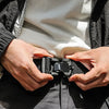يدان تعدلان حزامًا مغناطيسيًا تكتيكيًا أسود قابل للفصل تحت سترة رمادية.