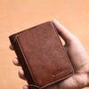 A hand holds a brown luxury PU leather men's wallet with a stitched edge against a light background.