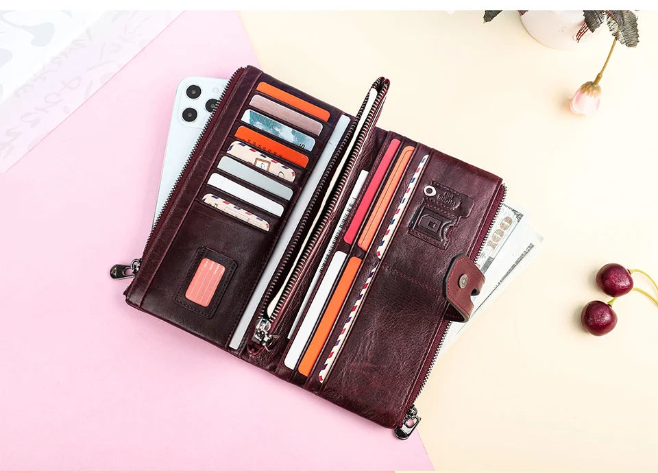 A brown genuine leather vintage clutch wallet is shown open, displaying various colored cards and documents on a light pink b